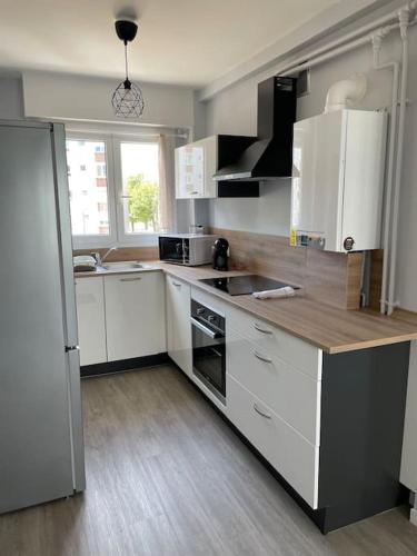 une cuisine avec des armoires blanches et un comptoir en bois dans l'établissement GDK locations meublés DUNKERQUE, à Dunkerque