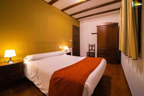 a bedroom with a bed and a dresser with a lamp at Apartamentos Los Olivos in Alcalá del Júcar