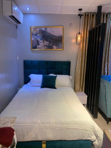 a bedroom with a large bed with white sheets at Teal Snug Open-Plan Studio Unit in Lekki Phase 1-Netflix, Wi-Fi, 24-7 Light, Washer, Kitchen in Lagos
