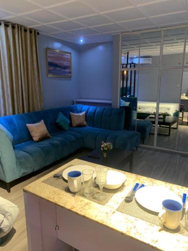 a living room with a blue couch and a table at Teal Snug Open-Plan Studio Unit in Lekki Phase 1-Netflix, Wi-Fi, 24-7 Light, Washer, Kitchen in Lagos