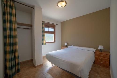 a bedroom with a white bed and a window at Apartamentos Berrocal in Alcalá del Júcar