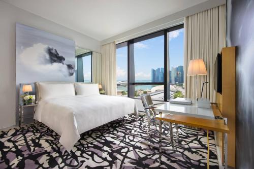 a bedroom with a bed and a desk and windows at JW Marriott Hotel Singapore South Beach in Singapore