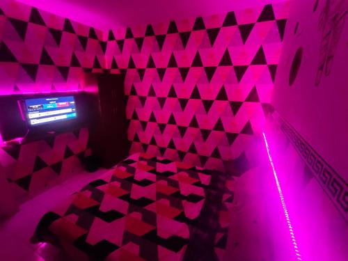 a purple room with a bed with pink lights at RDTROOM TRANSIT At Aeropolis in Teko