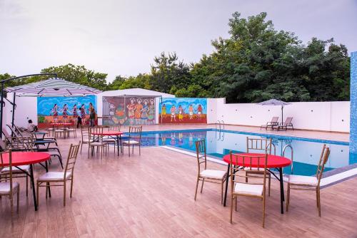 una piscina con tavoli e sedie accanto a una piscina di Welcome Resorts And Spa 