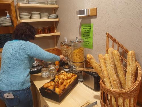 Eine Frau, die an einer Theke steht und Essen zubereitet. in der Unterkunft Logis Hôtel-restaurant Les Coudercous in Saint-Chély-dʼAubrac