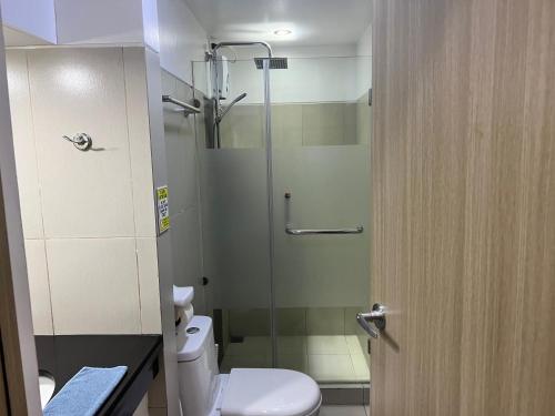 a bathroom with a toilet and a glass shower at De Luxe, Standard and Studio Suites -The Breeze Residences-close to Airport,Mall of Asia, US Embassy in Manila
