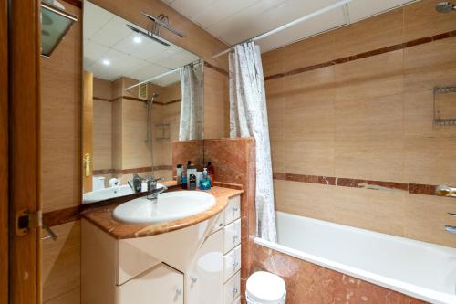 Un baño con lavabo, bañera y espejo. en Comfy Downtown + Private terrace, en Barcelona
