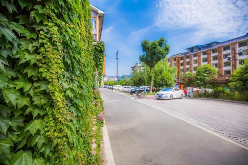 a green wall with cars parked on the side of a street at Tea House in Zhangjiajie
