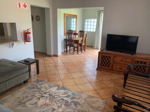 a living room with a television and a table with chairs at Bougain Villa Guest House in Polokwane