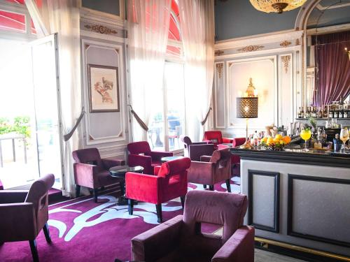 ein Zimmer mit Stühlen und eine Bar in einem Restaurant in der Unterkunft Le Grand Hotel de Cabourg - MGallery Hotel Collection in Cabourg