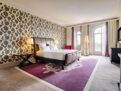 a bedroom with a large bed and a purple rug at Le Grand Hotel de Cabourg - MGallery Hotel Collection in Cabourg