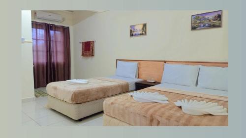 ein Hotelzimmer mit 2 Betten und einem Fenster in der Unterkunft Tunas Cottage 2 in Kuah