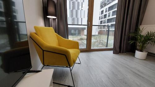 a yellow chair in a room with a window at Apartment Mokotów blisko lotniska Chopina in Warsaw
