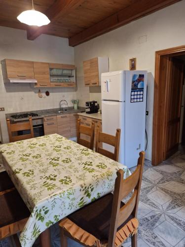 uma cozinha com uma mesa e um frigorífico branco em Agriturismo il fosso em Cutigliano