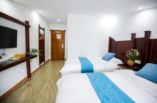 a hotel room with two beds and a flat screen tv at Tea House in Zhangjiajie