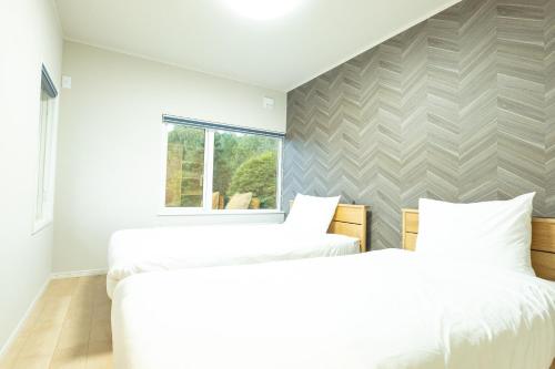 dwa łóżka w pokoju z oknem w obiekcie VILLA LOUISA w mieście Furano