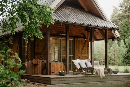 a wooden cabin with a porch and a patio at ALNUS KIEMAS in Kampiškiai