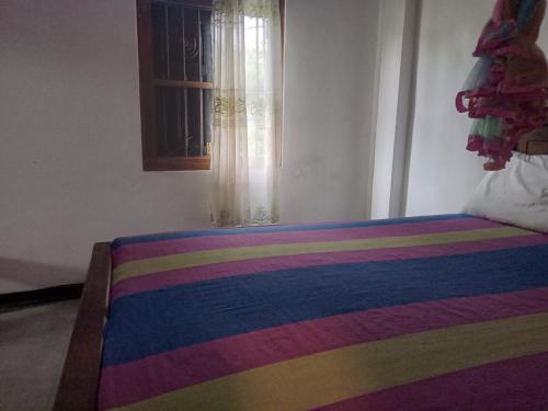 a bedroom with a rainbow bed with a window at Lyon Villa in Talpe
