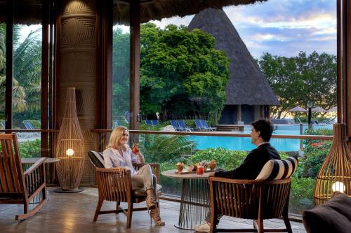 a man and woman sitting at a table in a restaurant at Sheraton New Caledonia Deva Spa & Golf Resort in Bourail