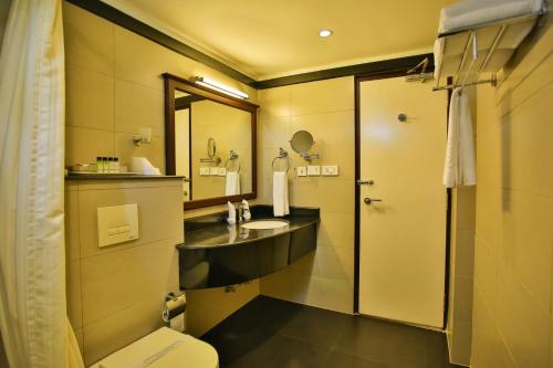 uma casa de banho com um lavatório, um WC e um espelho. em Harbour Hotels em Pallipuram