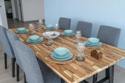 a wooden table with chairs and plates and glasses at Heaven Crest Vacation Homes Dubai Marina - 4 Bedroom Suite with Marina View near JBR Beach, Free Parking, Wi-Fi, Gym and Pool in Dubai