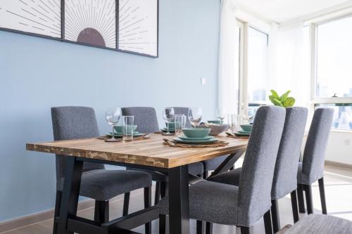 a dining room table with gray chairs and a wooden table at Heaven Crest Vacation Homes Dubai Marina - 4 Bedroom Suite with Marina View near JBR Beach, Free Parking, Wi-Fi, Gym and Pool in Dubai