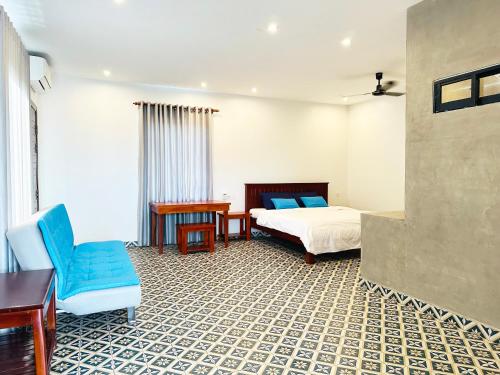 a bedroom with a bed and a desk and a chair at Eco Inn in Phumĭ Réach Born