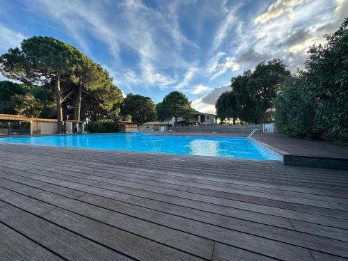 a blue swimming pool with a wooden deck at T4 neuf Porto Vecchio Calarossa in Lecci