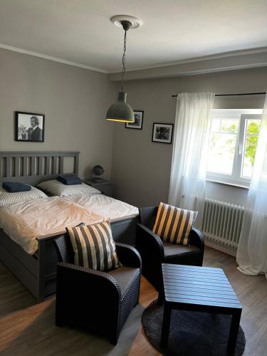 a bedroom with a bed and chairs and a window at Villa Moselstrand in Moselkern