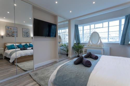 a bedroom with a large bed with a flat screen tv at Luxury Apartment in Willesden in London