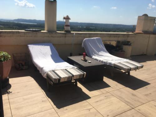 2 lits sur un toit avec une table et un phare dans l'établissement Châteauneuf du Pape - Chez Marie - suite loft au roof top, idéale pour 2 - Vue panoramique, terrasse, Jacuzzi en option, à Châteauneuf-du-Pape