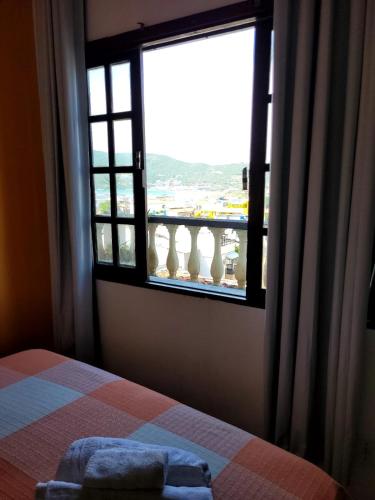 a bedroom with a window with a view of the ocean at Pousada Mar Dos Anjos in Arraial do Cabo