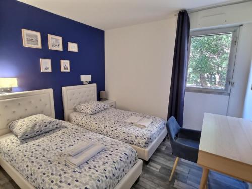 une chambre avec deux lits, une table et une fenêtre dans l'établissement Appartement T3 72m2 Marselle St Anne Borély Proche plage, à Marseille