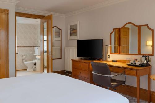格洛斯特Hilton Puckrup Hall Hotel & Golf Club, Tewkesbury的一间卧室，配有一张床和一张带电视的书桌