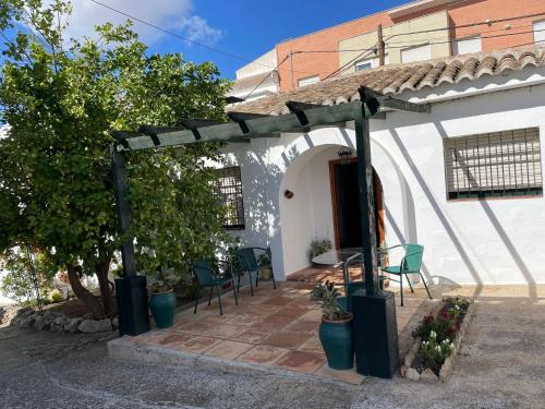 eine Terrasse vor einem weißen Haus mit einem Tisch und Stühlen in der Unterkunft Agradable casa con jardín y chimenea interior in Baena