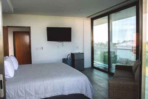 1 dormitorio con cama, sofá y TV en Casa de tus Sueños en Holbox Island
