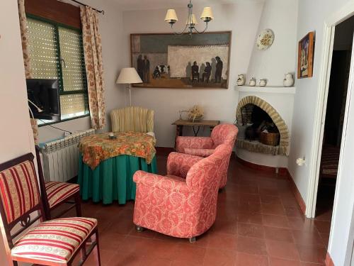 uma sala de estar com cadeiras, uma mesa e uma lareira em Agradable casa con jardín y chimenea interior em Baena
