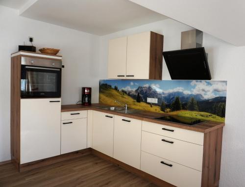 a kitchen with a counter with a painting on the wall at Hofer's Wiesenheim in Zell am Ziller
