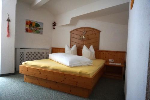 a bedroom with a wooden bed with white pillows at Hofer's Wiesenheim in Zell am Ziller