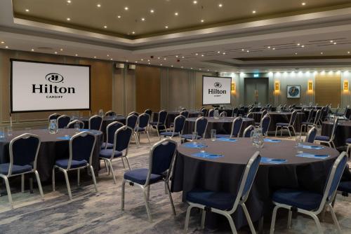 a conference room with tables and chairs and a screen at Hilton Cardiff in Cardiff