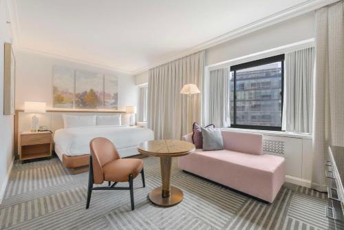 ein Hotelzimmer mit einem Bett, einem Stuhl und einem Tisch in der Unterkunft Capital Hilton in Washington