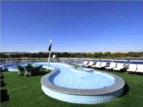 une grande piscine entourée de chaises longues. dans l'établissement Luis Luxor Nile Cruise, à Louxor