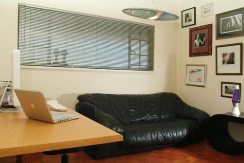 Walk to Sandton City في جوهانسبرغ: غرفة معيشة مع أريكة جلدية سوداء وطاولة مع الكمبيوتر المحمول