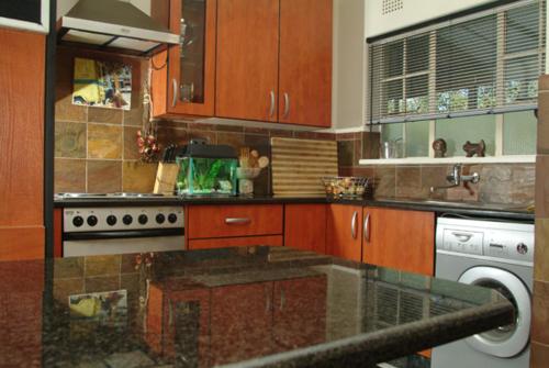 a kitchen with wooden cabinets and a glass counter top at Walk to Sandton City in Johannesburg