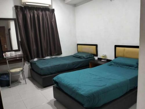 a room with two beds and a table and a desk at FLG Motel in Alor Setar