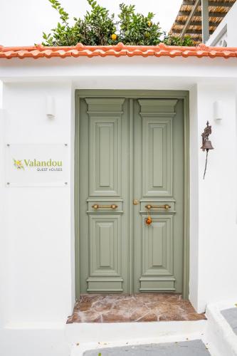 a green door on the side of a white building at Valandou Guesthouses in Karpathos Town