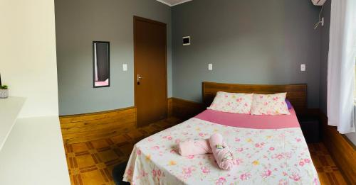 a bedroom with a bed with two pink slippers on it at Chalés do Parque Hospedagem in Penha