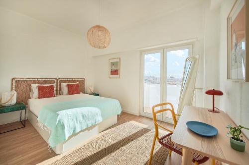 a bedroom with a bed and a table and a window at Seaview & Sunset Balcony Charm, BY TimeCooler in Setúbal
