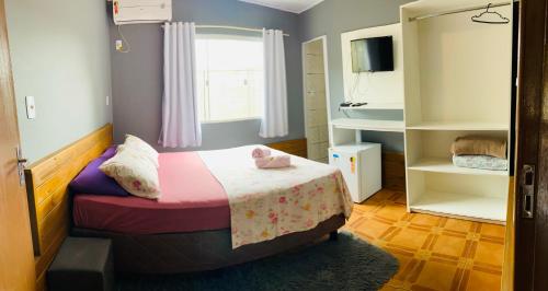 a small bedroom with a bed and a window at Chalés do Parque Hospedagem in Penha