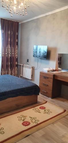 1 dormitorio con cama, mesa y alfombra en 1 комнатная квартира в Павлодаре, en Pavlodar